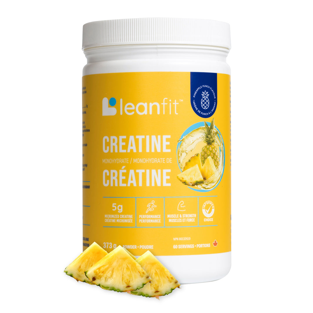 A white plastic tub of leanfit Creatine Monohydrate with a bright yellow label, shown on a white background with three pineapple slices in front.