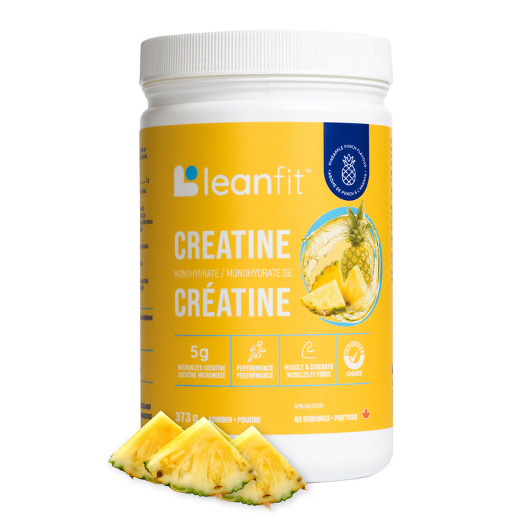 A white plastic tub of leanfit Creatine Monohydrate with a bright yellow label, shown on a white background with three pineapple slices in front.