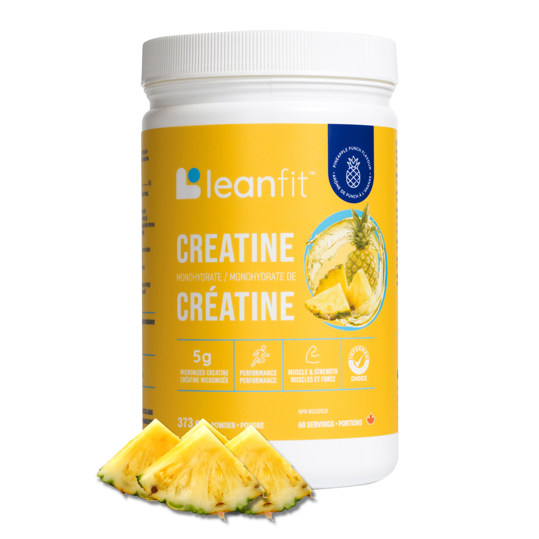 A white plastic tub of leanfit Creatine Monohydrate with a bright yellow label, shown on a white background with three pineapple slices in front of the tub.